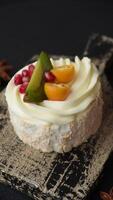 Piece of sweet meringue with citrus, kiwi and pomegranate seeds on a dark concrete background video