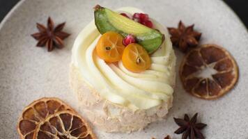 Piece of sweet meringue with citrus, kiwi and pomegranate seeds on a dark concrete background video