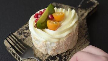 Piece of sweet meringue with citrus, kiwi and pomegranate seeds on a dark concrete background video