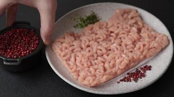 Raw minced chicken with salt, spices and herbs on a dark concrete background video