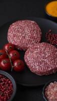 Fresh raw ground beef burger patty with salt and spices on textured concrete background video