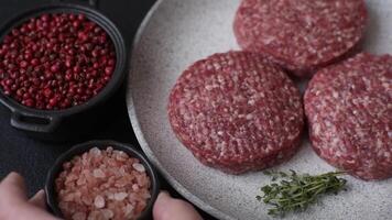 Fresh raw ground beef burger patty with salt and spices on textured concrete background video