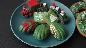Sweet Madeleines desserts covered with chocolate in Christmas colors, with various toppings on a dark concrete background video