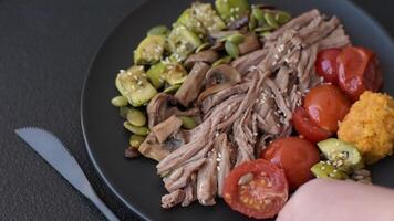 Boiled beef with vegetables, grains, seeds and spices in a ceramic plate on a dark concrete background video