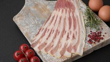 Fresh raw bacon sliced with spices and herbs on a dark concrete background video