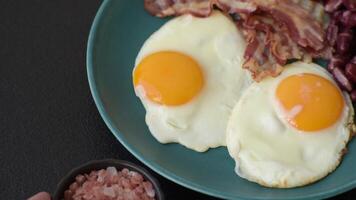 English breakfast with fried eggs, bacon, beans, tomatoes, spices and herbs. A hearty and nutritious start of the day video