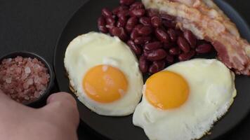 English breakfast with fried eggs, bacon, beans, tomatoes, spices and herbs. A hearty and nutritious start of the day video