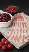 Fresh raw bacon sliced with spices and herbs on a dark concrete background video