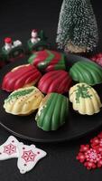 Sweet Madeleines desserts covered with chocolate in Christmas colors, with various toppings on a dark concrete background video
