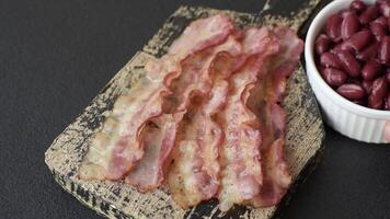 Bacon sliced, grilled with salt and spices on a dark concrete background video