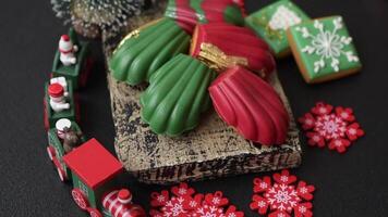 Sweet Madeleines desserts covered with chocolate in Christmas colors, with various toppings on a dark concrete background video