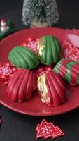 Sweet Madeleines desserts covered with chocolate in Christmas colors, with various toppings on a dark concrete background video