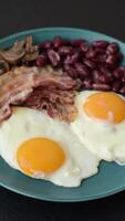 English breakfast with fried eggs, bacon, beans, tomatoes, spices and herbs. A hearty and nutritious start of the day video