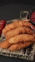 Hot crispy shrimp breaded with salt and spices with white sauce on a dark concrete background video
