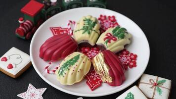 Sweet Madeleines desserts covered with chocolate in Christmas colors, with various toppings on a dark concrete background video