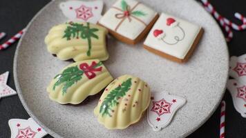 Sweet Madeleines desserts covered with chocolate in Christmas colors, with various toppings on a dark concrete background video