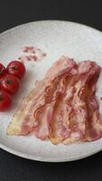 Bacon sliced, grilled with salt and spices on a dark concrete background video
