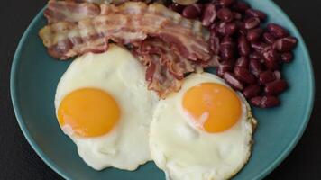 English breakfast with fried eggs, bacon, beans, tomatoes, spices and herbs. A hearty and nutritious start of the day video