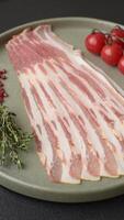 Fresh raw bacon sliced with spices and herbs on a dark concrete background video