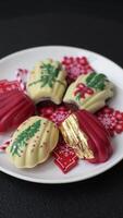 Sweet Madeleines desserts covered with chocolate in Christmas colors, with various toppings on a dark concrete background video