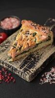 Pieces of quiche with salmon, spinach or broccoli, salt and spices on a dark concrete background video
