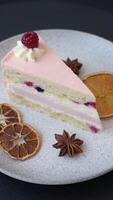 Piece of sweet cake with pink cream with raspberry flavor, with shortbread, cheesecake on a dark concrete background video