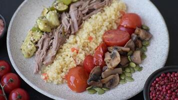 Boiled beef with vegetables, grains, seeds and spices in a ceramic plate on a dark concrete background video