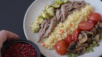 Boiled beef with vegetables, grains, seeds and spices in a ceramic plate on a dark concrete background video