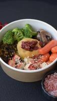 Boiled beef with vegetables, grains, seeds and spices in a ceramic plate on a dark concrete background video