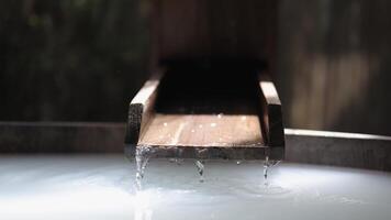 Close-up view of water flowing into a bathtub against wooden, natural background. This modern bathroom scene combines sleek design with natural elements, creating spa. Advertising. Selective focus video