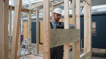 Worker using drill and working on building development of prefabricated home. Process of construction modern modular house in factory video