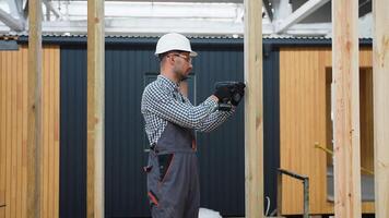 Worker using drill and working on building development of prefabricated home. Process of construction modern modular house in factory video