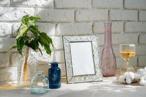 Mockup with a frame and dry flowers in a vase on a white table photo