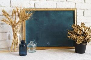 Mockup with a frame and dry flowers in a vase on a white table photo