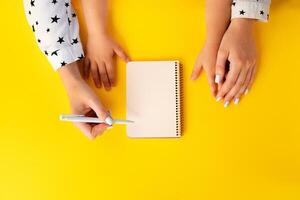 Mother and child hands writing in a notepad, top view photo