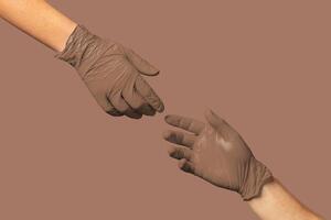 Hands in brown gloves exchanging an object against a neutral background, symbolizing cooperation and assistance photo