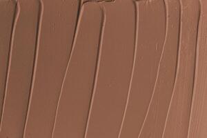 Smooth, creamy texture of rich chocolate frosting spread across a surface in warm brown tones photo
