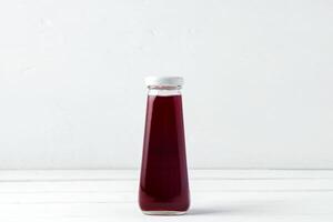 Small glass bottle of fresh juice on white background photo