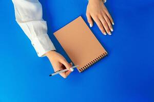 To do list. Top view of female hands writing in notebook photo