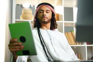 Young Arab businessman using digital tablet in an office photo