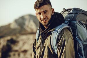 Young caucasian man traveler with big backpack hiking in the mountains photo