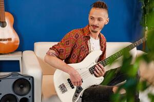 Young man guitar player sitting and performing on a couch photo