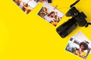 Photo camera with colorful printer photos on yellow background