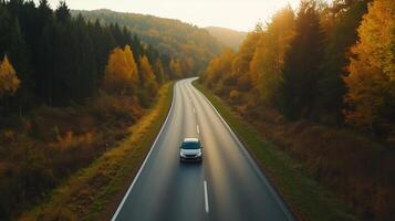 Scenic autumn drive on a winding road through a forested landscape during golden hour photo