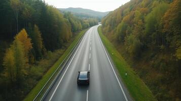 Scenic drive on a winding country road surrounded by autumn foliage and hills in the early morning photo