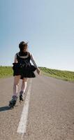 Attractive girl quickly accelerated on roller skates on road. Vertical footage video