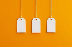 Three Blank White Tags Hanging on Orange Background photo