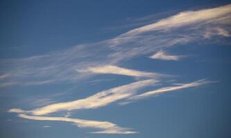Zigzag shaped band of cirrus clouds on blue sky photo