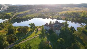 Castle at sunset by the lake. Ancient castle in a picturesque place. A castle, a lake and a small village, smoke spreads on the horizon. video