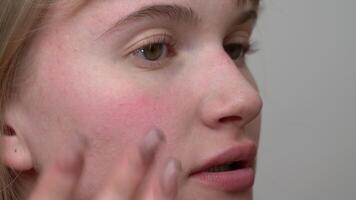 Applying blush to face with makeup brush, young woman uses finger to blend blush, process of creating natural-looking skin tone can be achieved. Extreme close-up view application process of cosmetics video